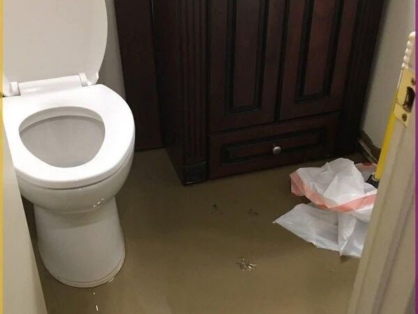A flooded bathroom with standing water across the floor