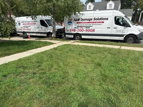 Two branded A&M Damage Solutions vans parked at a job